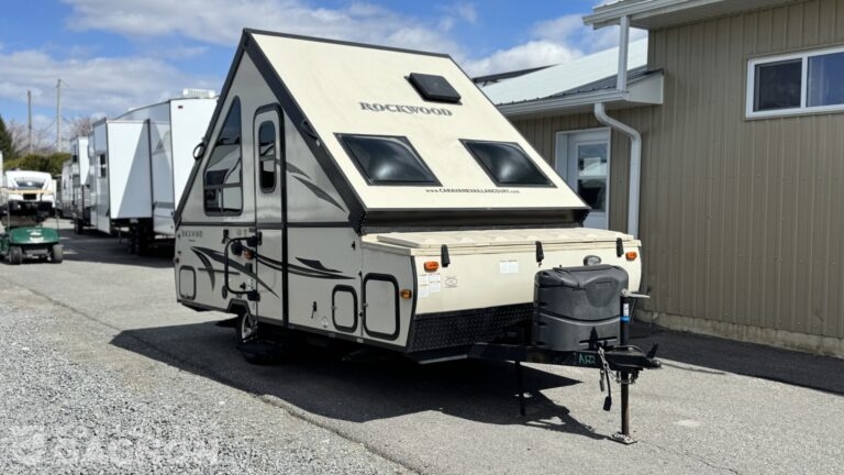 Tente roulotte usagée Rockwood A122S 2017 déployée avec structure rigide installée sur terrain de camping